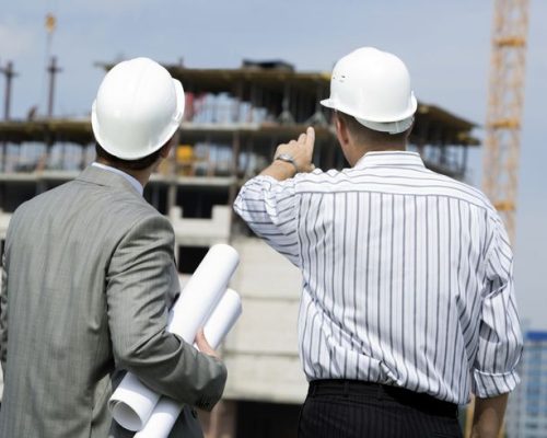 Rear shot of boss pointing at construction with worker near by Rear shot of boss pointing at construction with worker near by